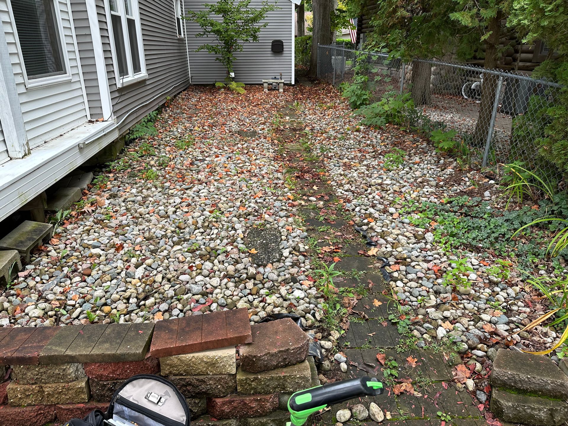 a backyard with a lot of rocks and a hose in front of a house .