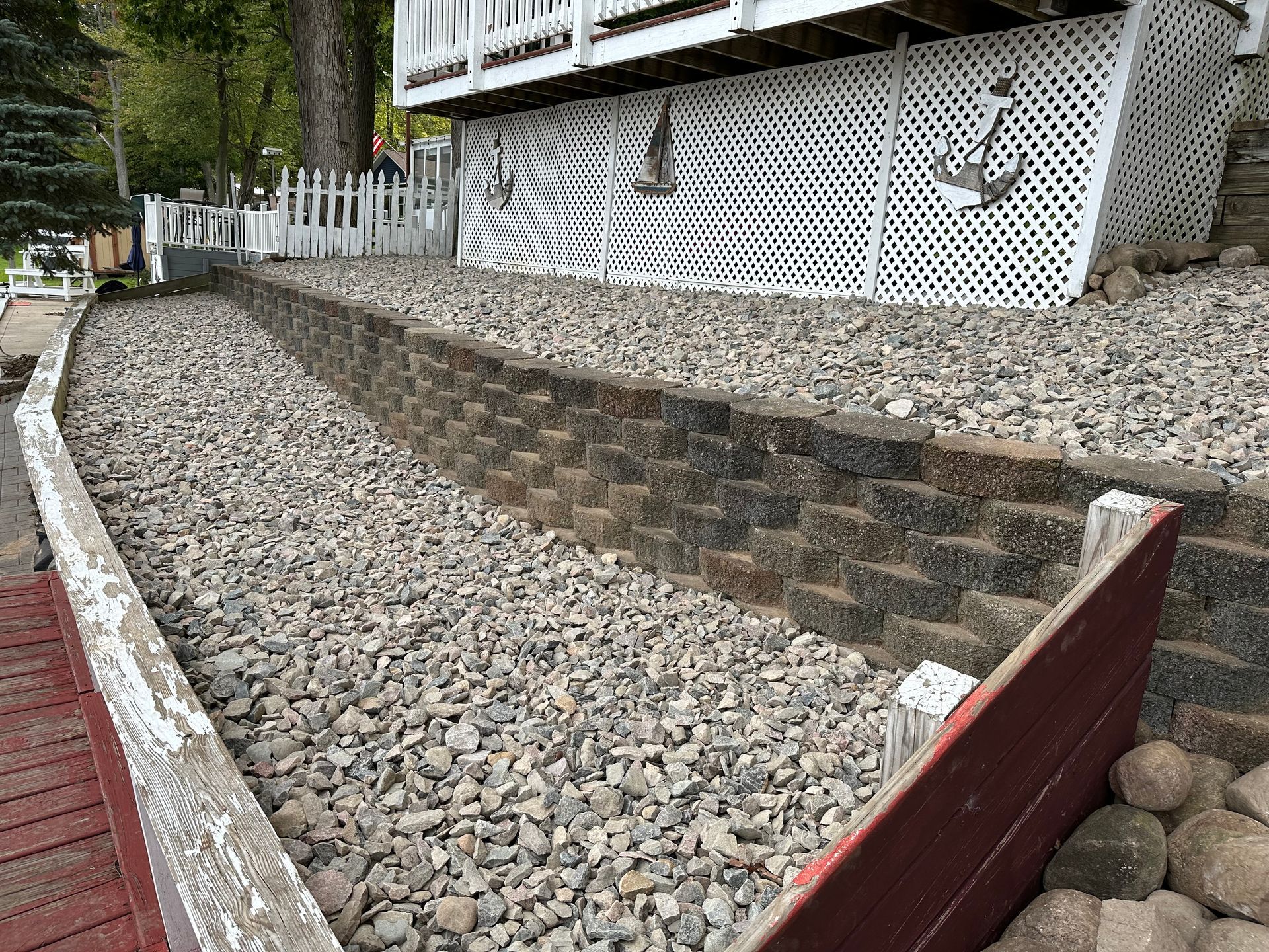 a brick wall surrounded by gravel in front of a house .