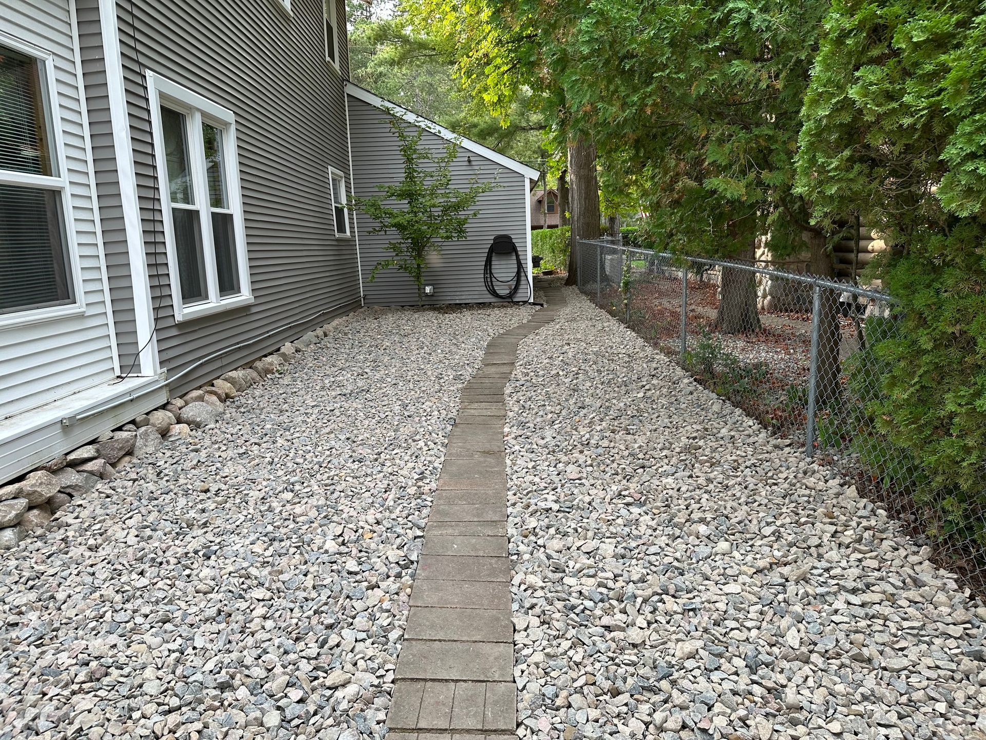 a gravel path leading to a house with a chain link fence .