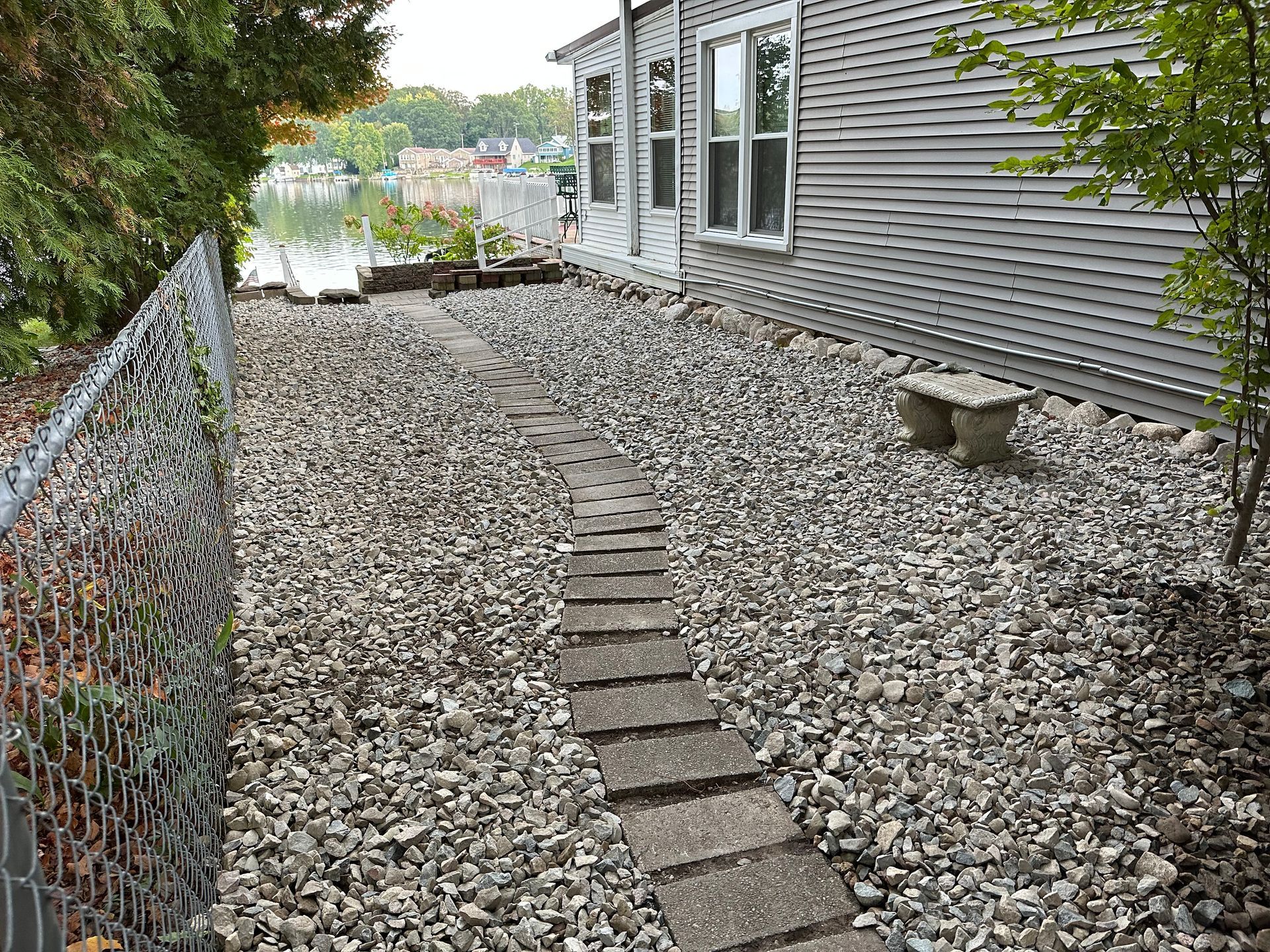 a path leading to a house surrounded by rocks and a chain link fence .