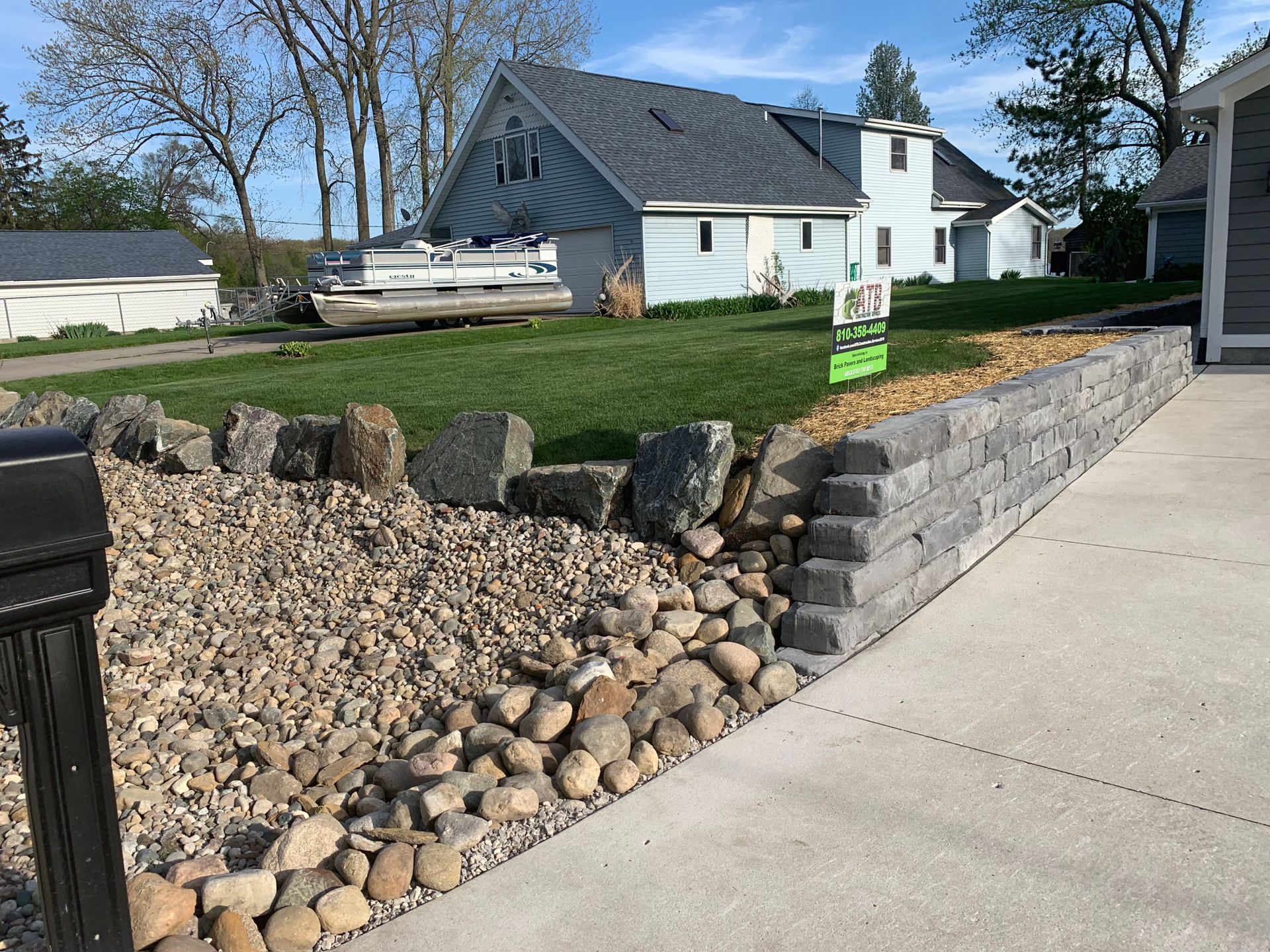 A brick wall is being built in a yard with trees in the background. retaining wall