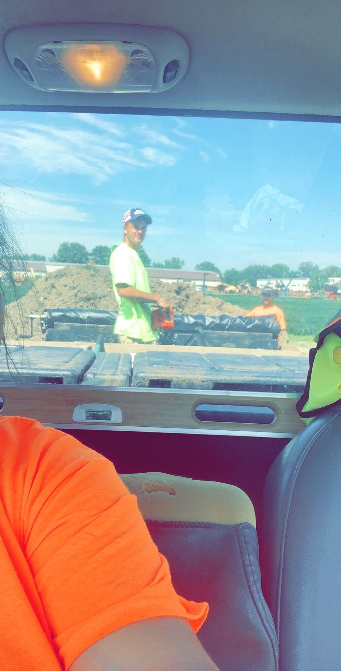 A man wearing a black hoodie and a green hat is giving a thumbs up. brick pavers. landscape