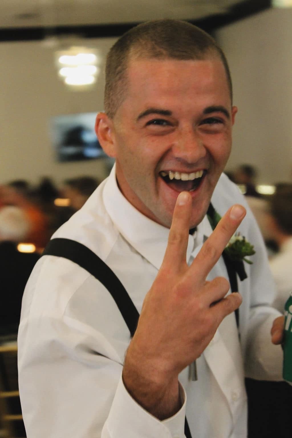 A man in a white shirt is giving the peace sign