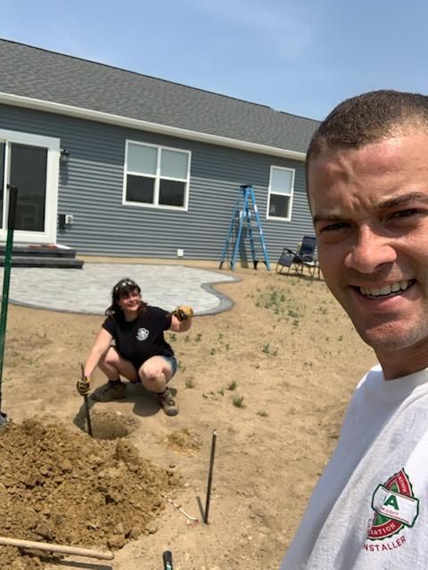 A woman standing on a ladder in front of a house. patio lights