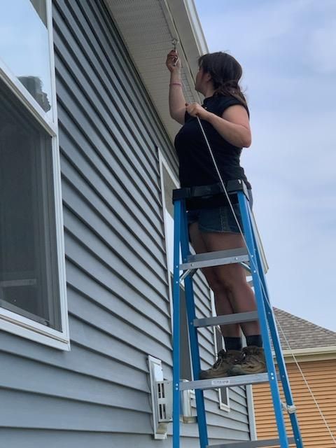 A man is standing on a patio in front of a house at night. Edison lighting