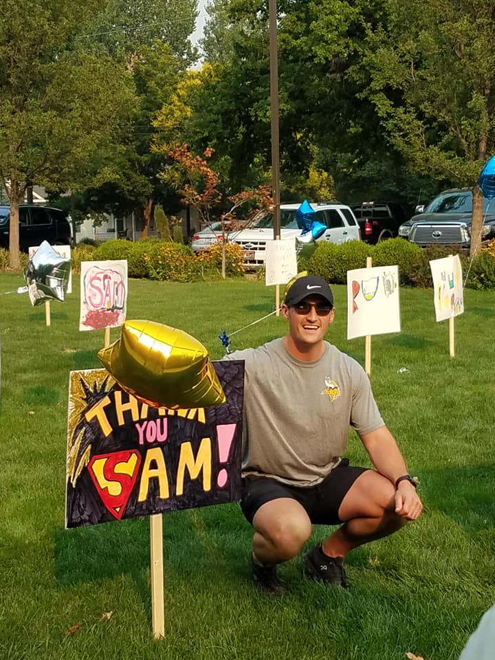 A man is squatting in front of a sign that says throw you cam