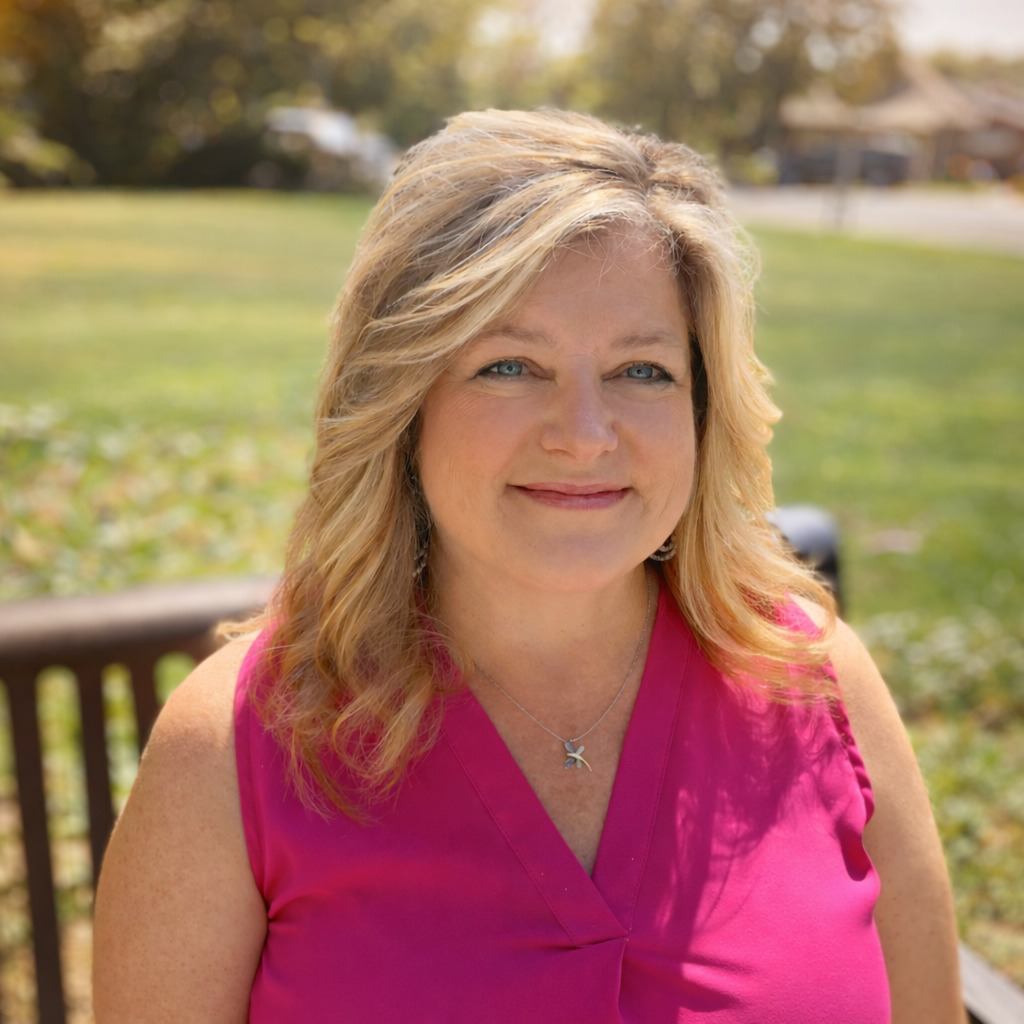 Woman in pink top sits on a park bench. Sunny outdoor background.