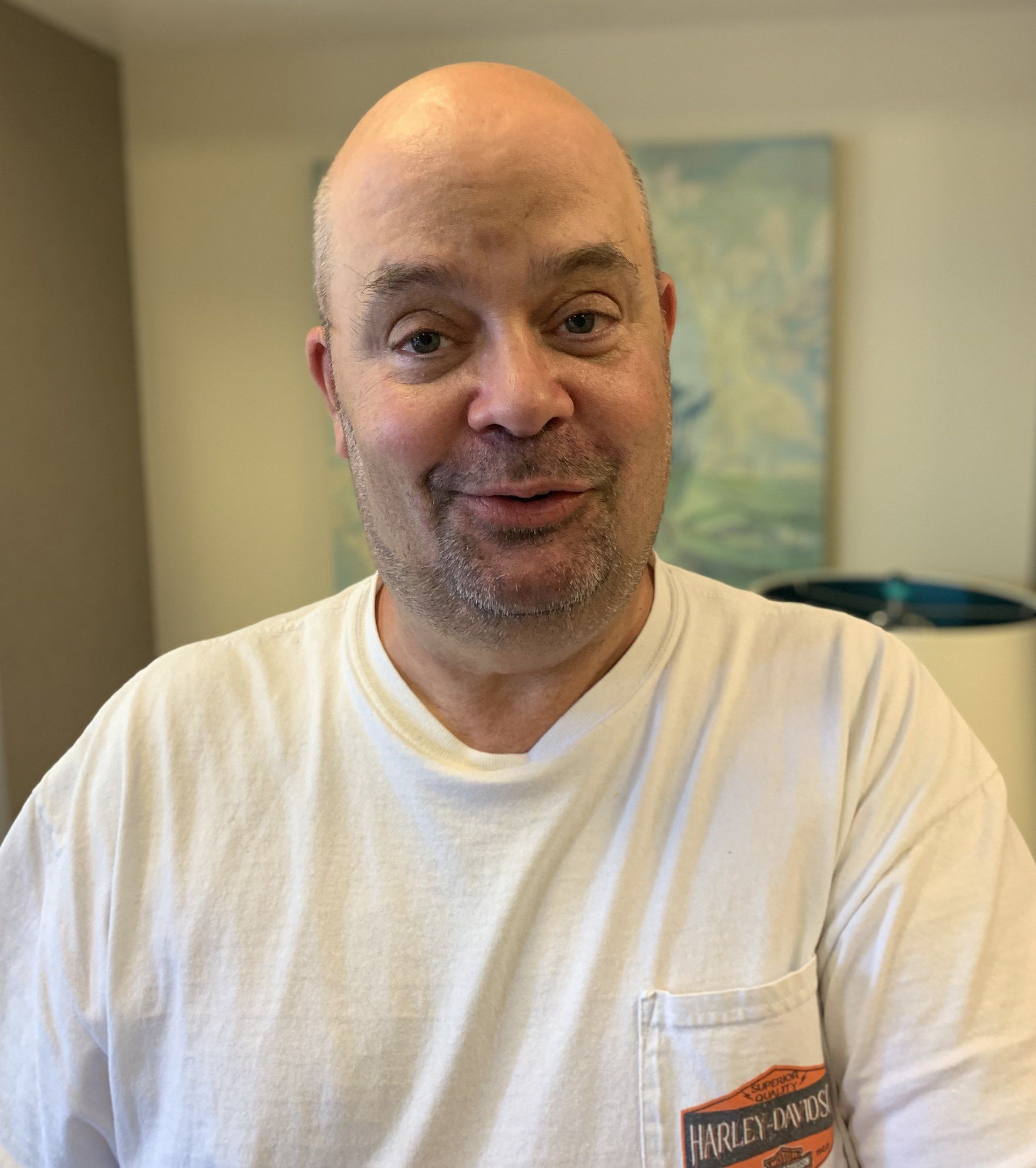 A bald man wearing a white harley davidson shirt