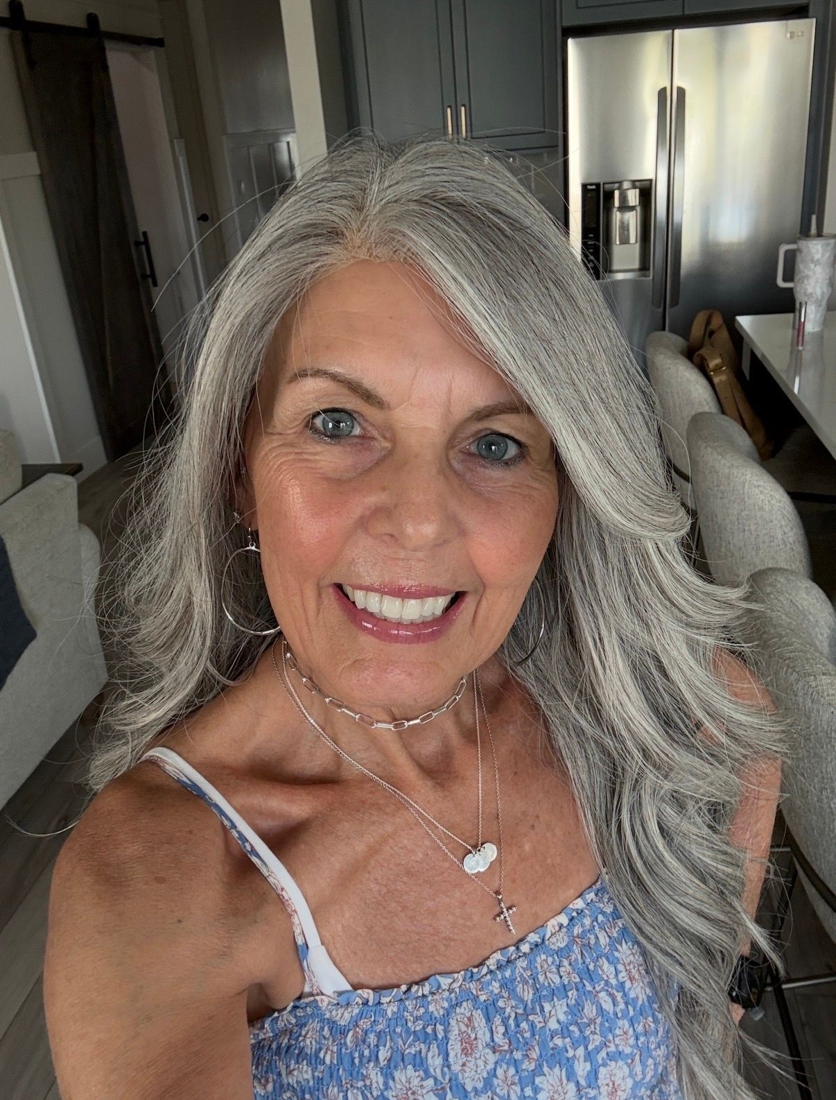 Blond woman smiling, wearing a red sweater, outdoors in front of a blurred background.