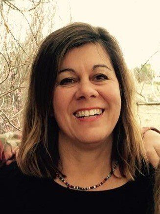 A close up of a woman wearing a necklace and smiling.