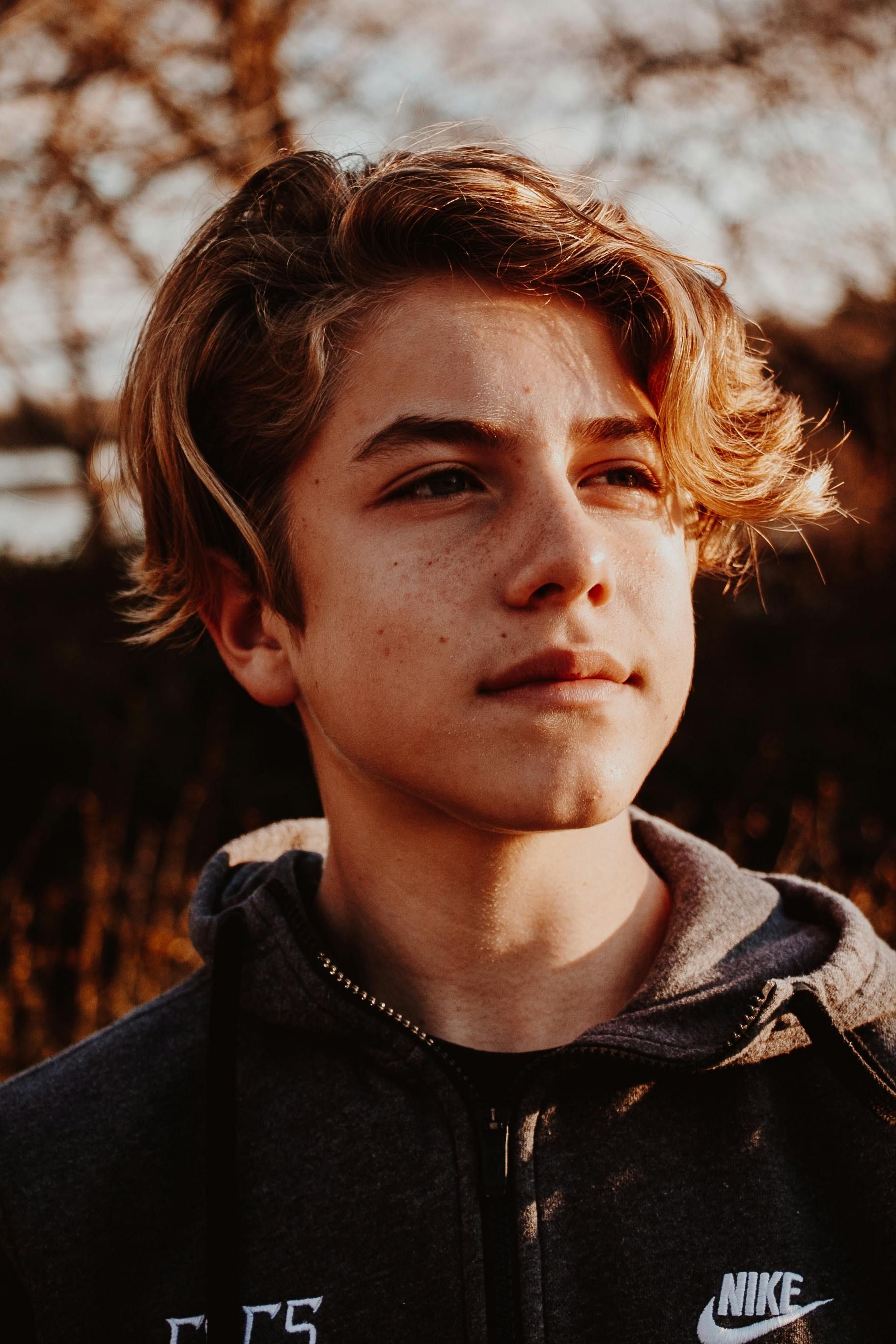 A young man wearing a nike hoodie is looking at the camera.