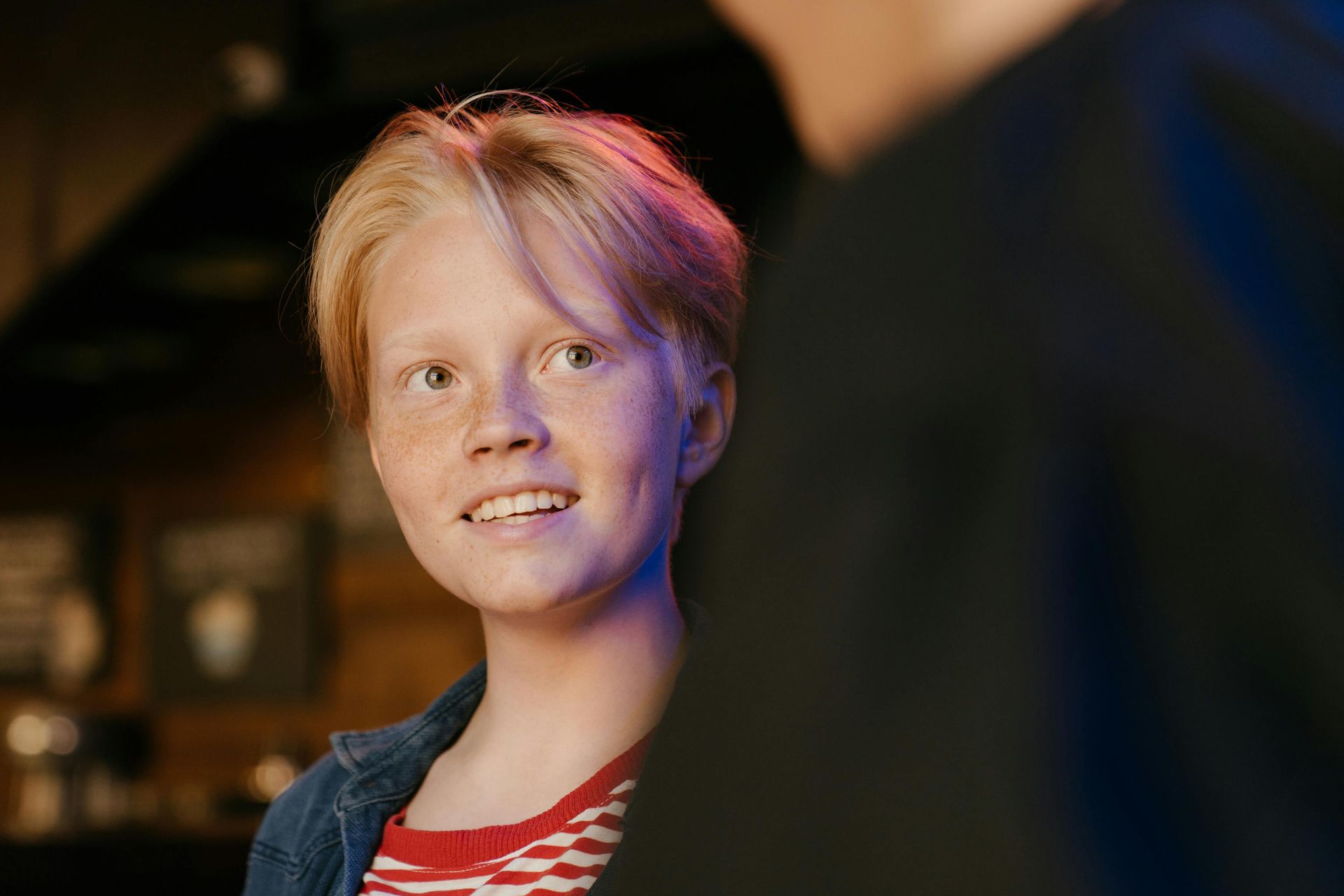 A young boy is standing next to a man in a dark room.