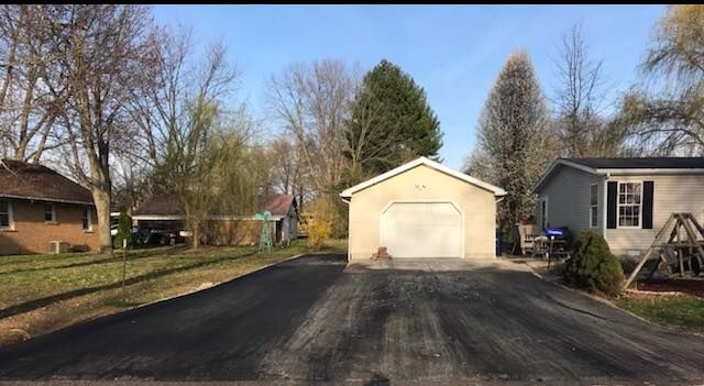 A driveway with a garage and a house in the background.
