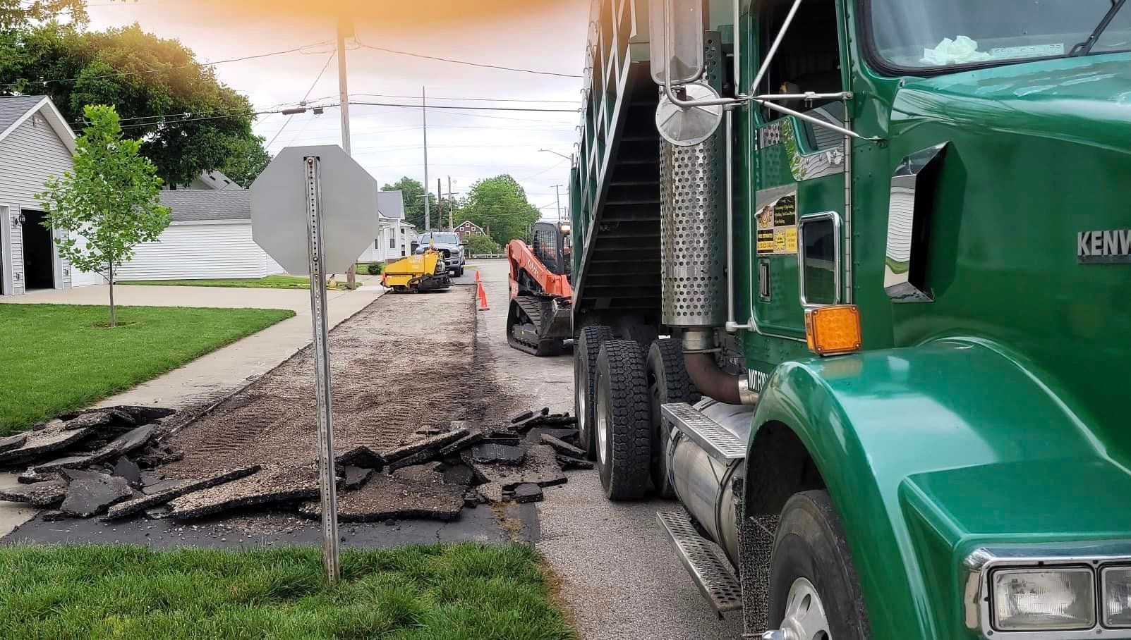 A green truck is parked on the side of the road.