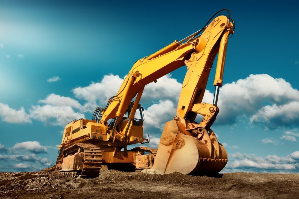 A large yellow excavator is working on a construction site.