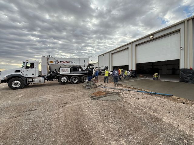 A truck is being loaded with concrete in front of a building.