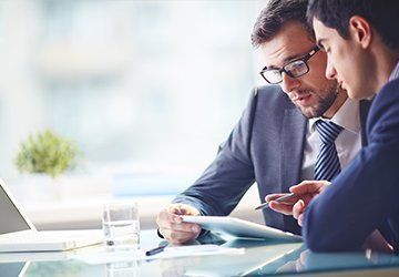 Two Men Are Sitting at a Table — Paton Hooke Lawyers & Conveyancers In Taree, NSW