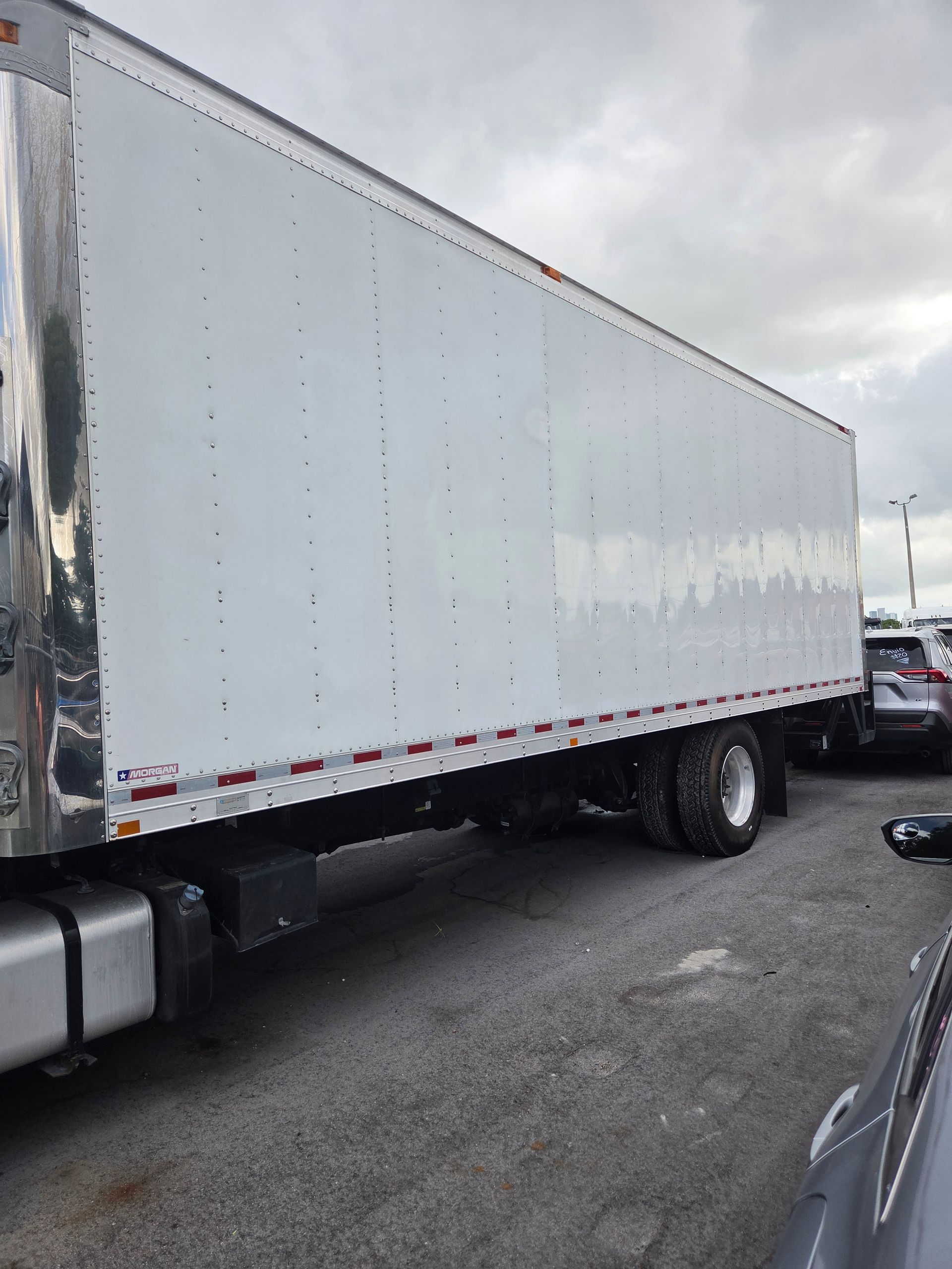 White semi-trailer truck parked on a paved lot on a cloudy day.