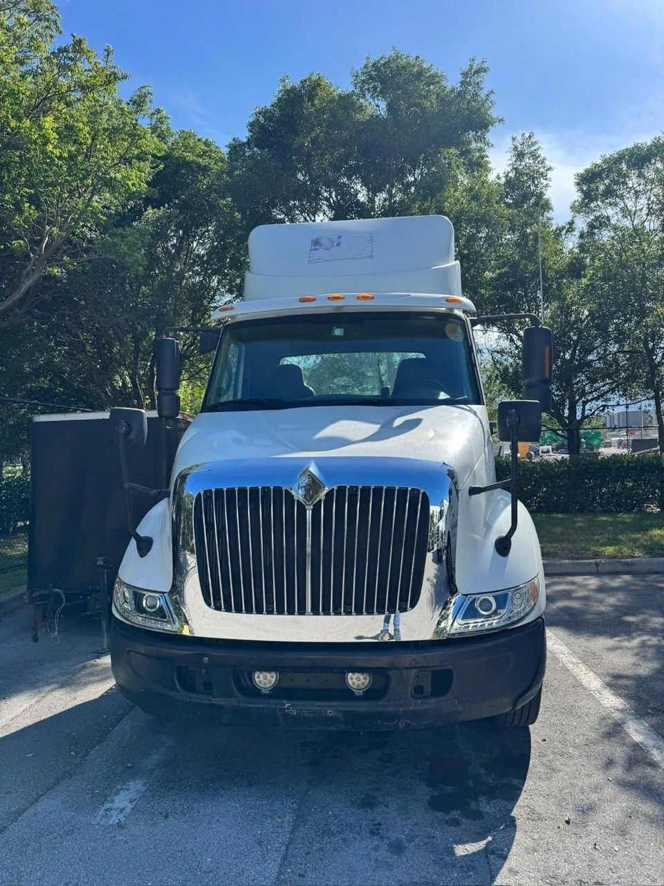 White International semi-truck parked in a lot, under a blue sky.