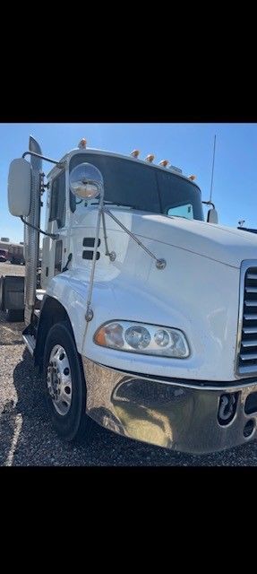 White semi-truck parked on a gravel lot.