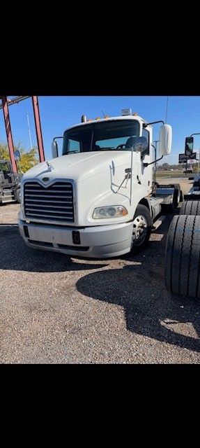 White Mack semi-truck in an outdoor setting under a blue sky. Front view.