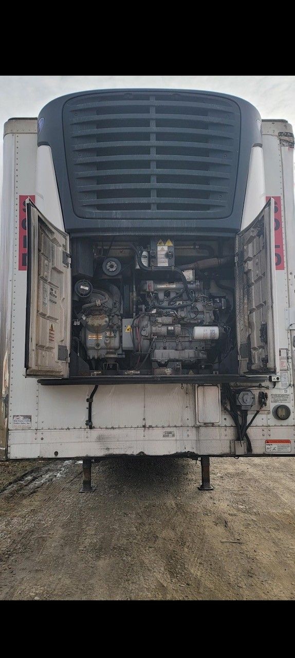 Rear view of a refrigerated trailer with open doors exposing the engine.