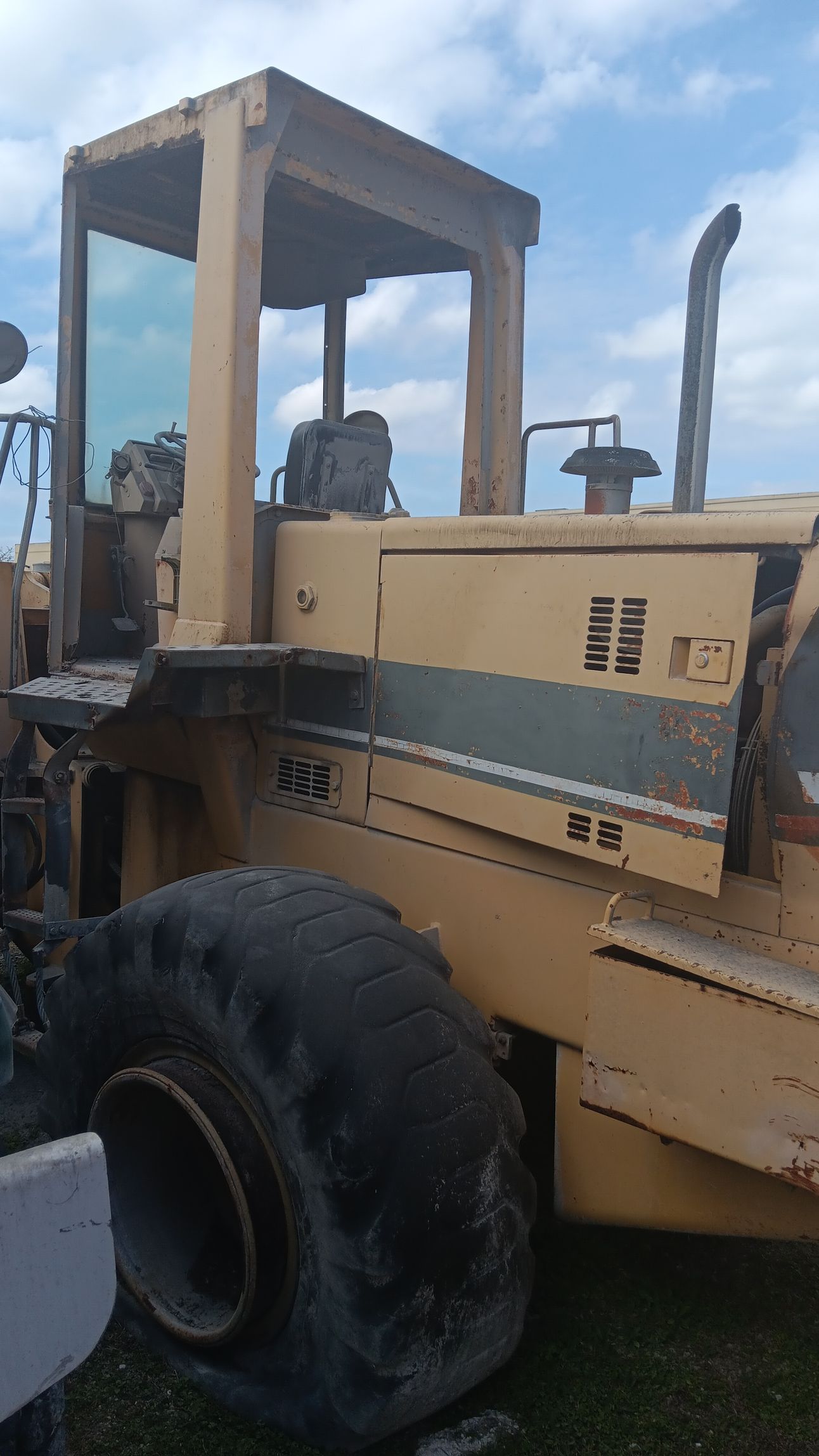 A yellow construction compactor machine with a partially open cab and large tires.