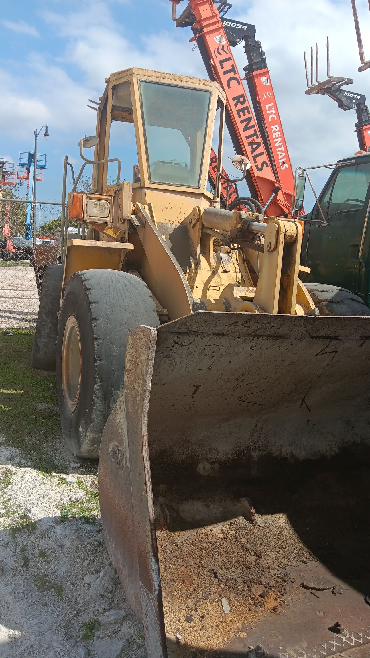 Yellow front-end loader outdoors, close-up of bucket, sunny day.