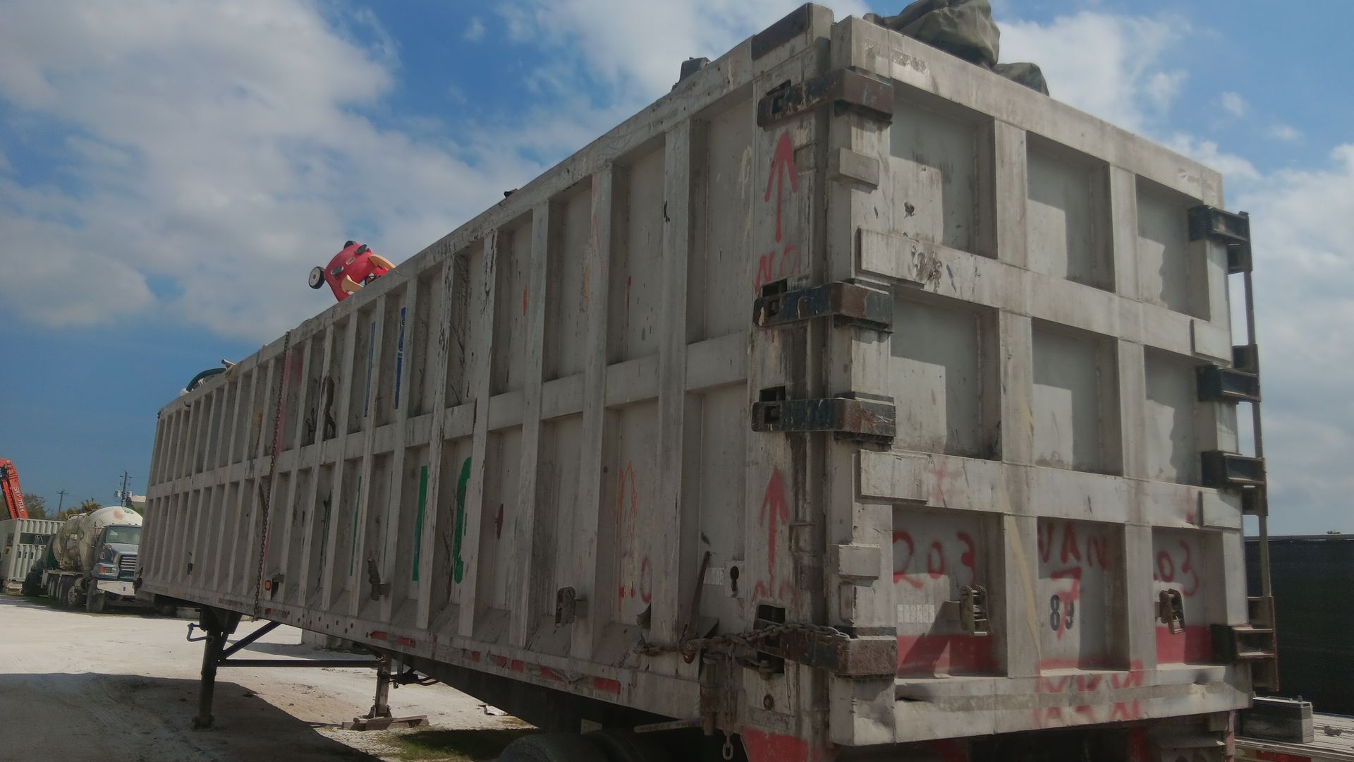 Large, weathered gray trailer on a sunny day. Someone in red is on top of it.