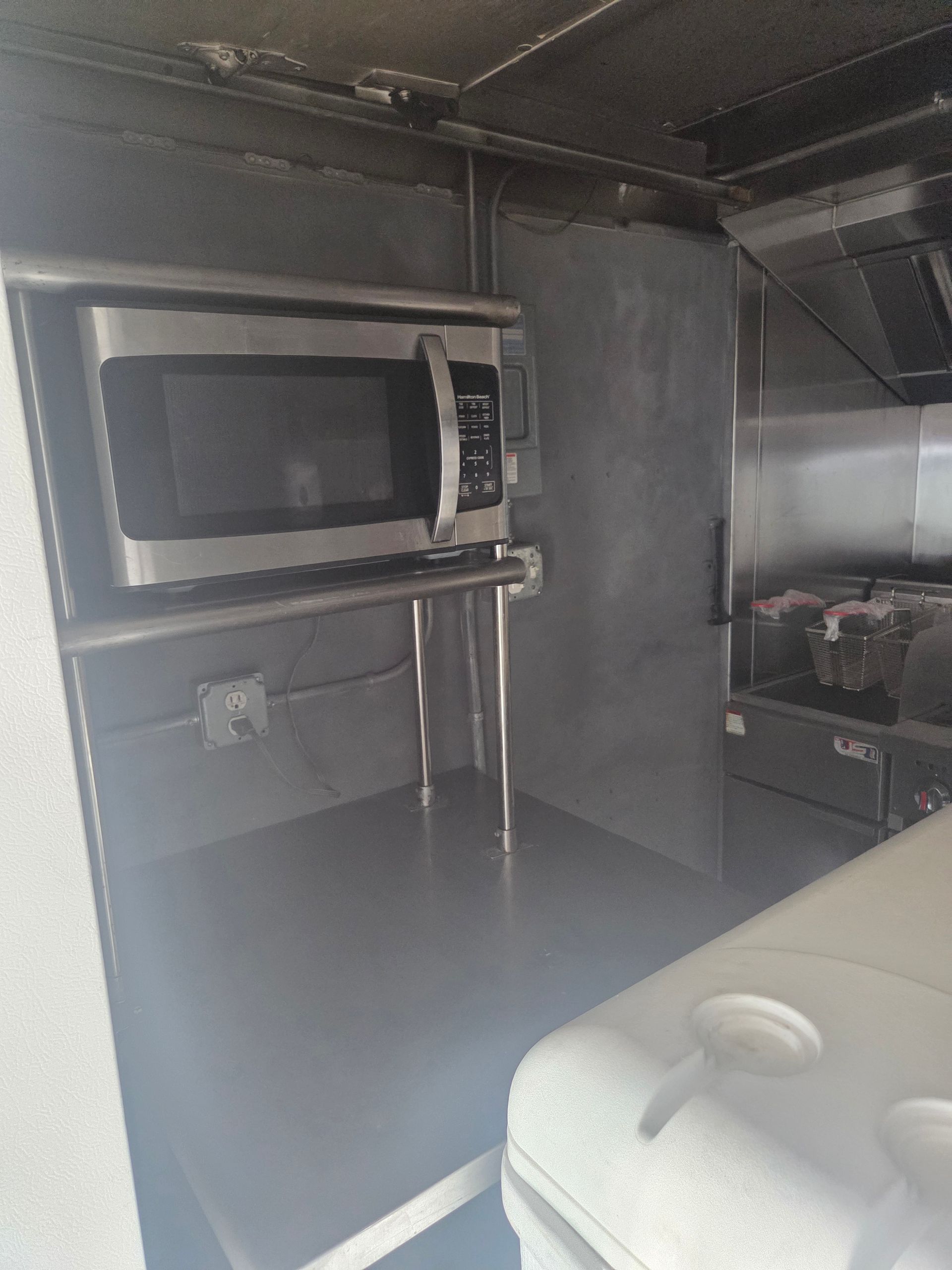 Stainless steel food truck kitchen with microwave and counter space.