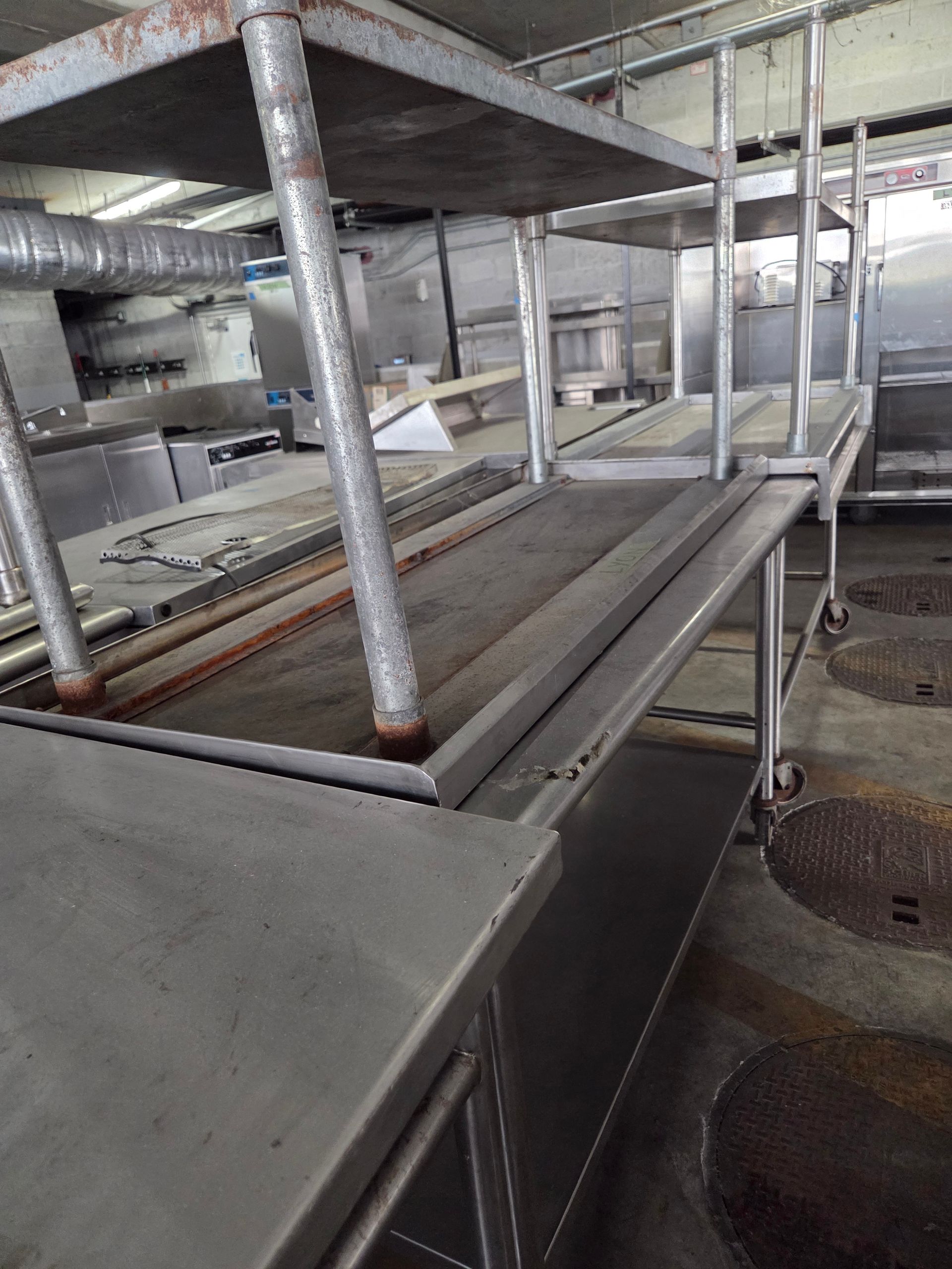 Stainless steel kitchen prep table with shelves; commercial kitchen interior.