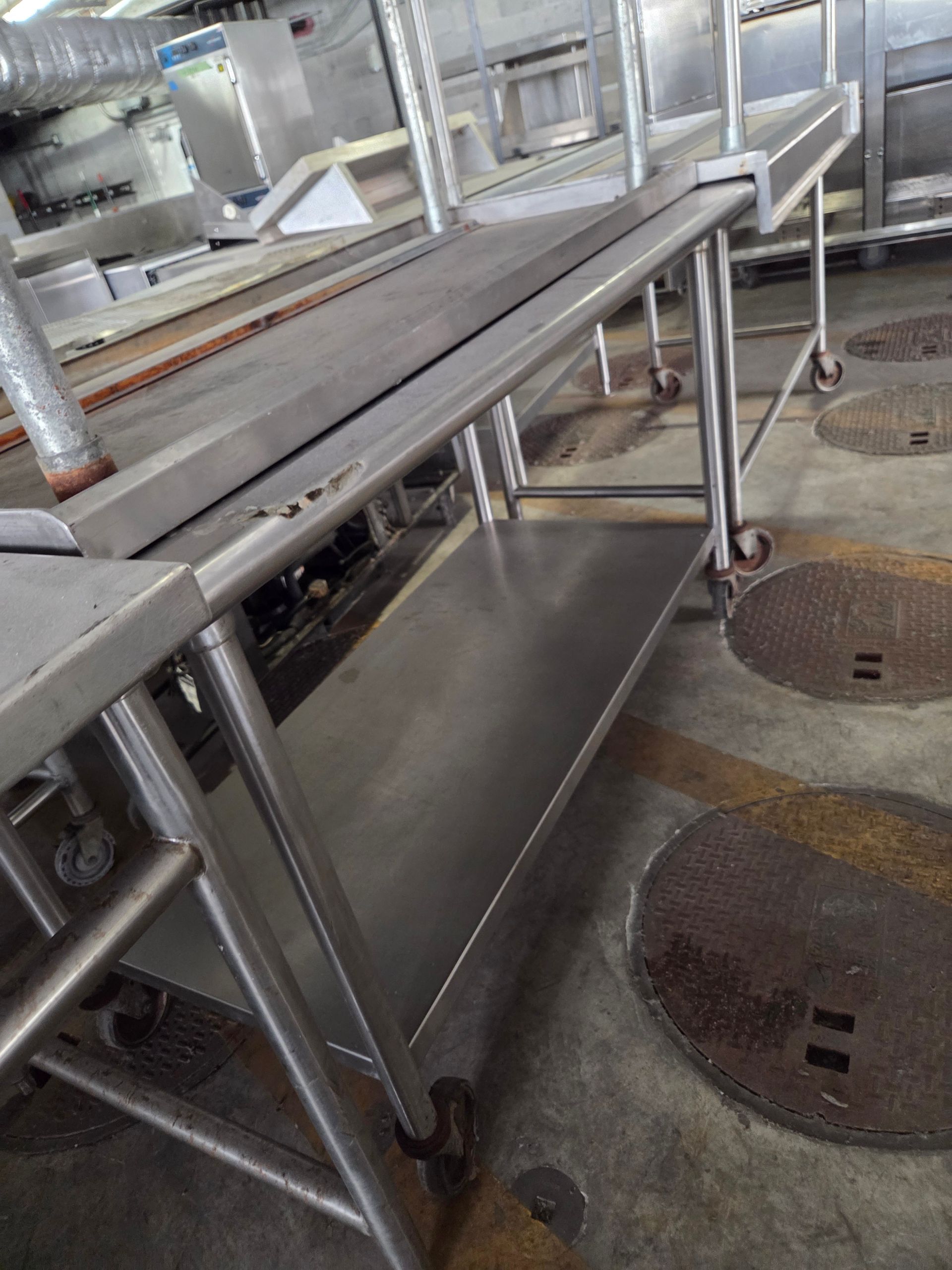 Stainless steel work table on wheels in a commercial kitchen.