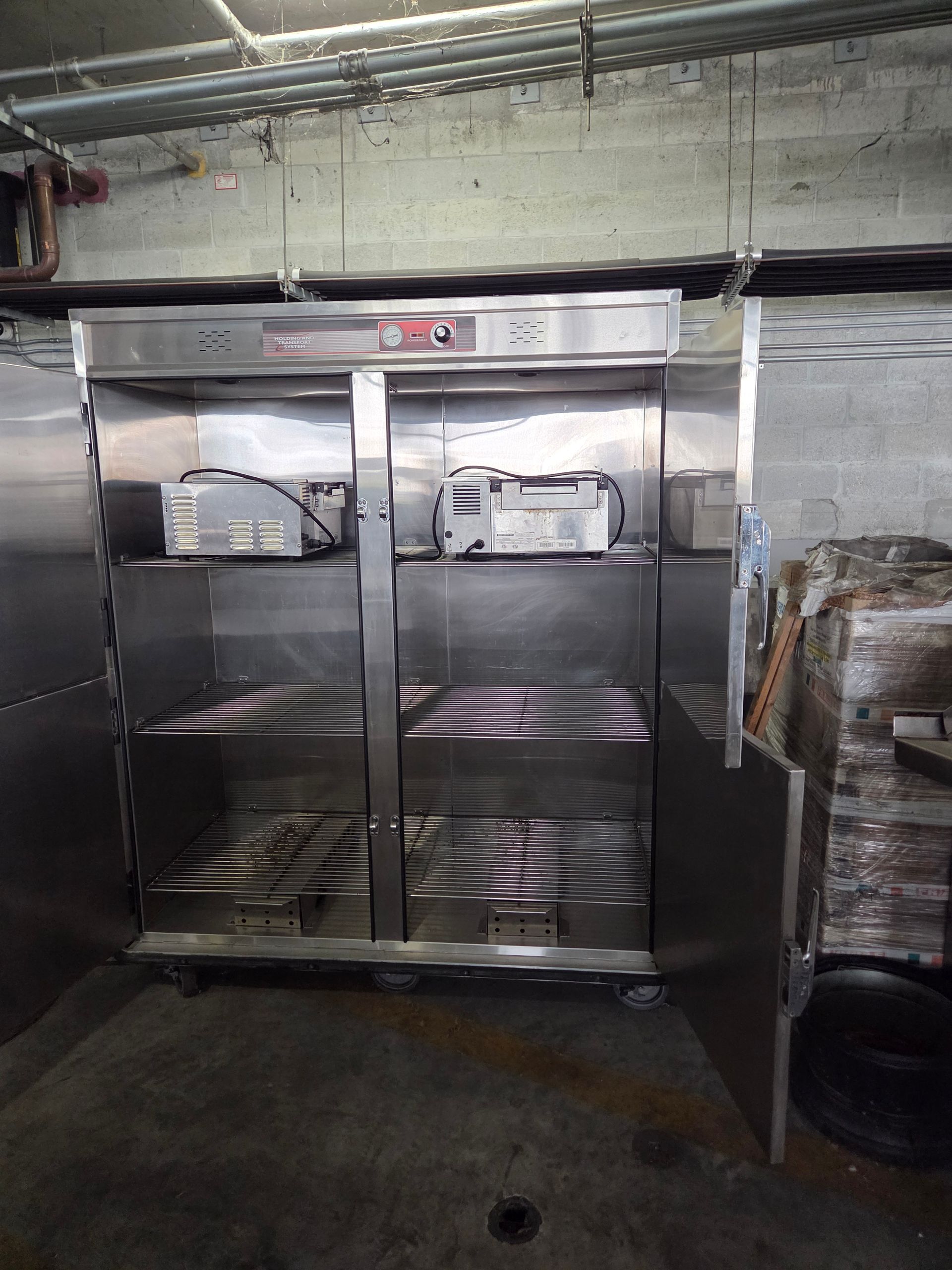 Stainless steel shelving unit with equipment inside, likely in a commercial setting.
