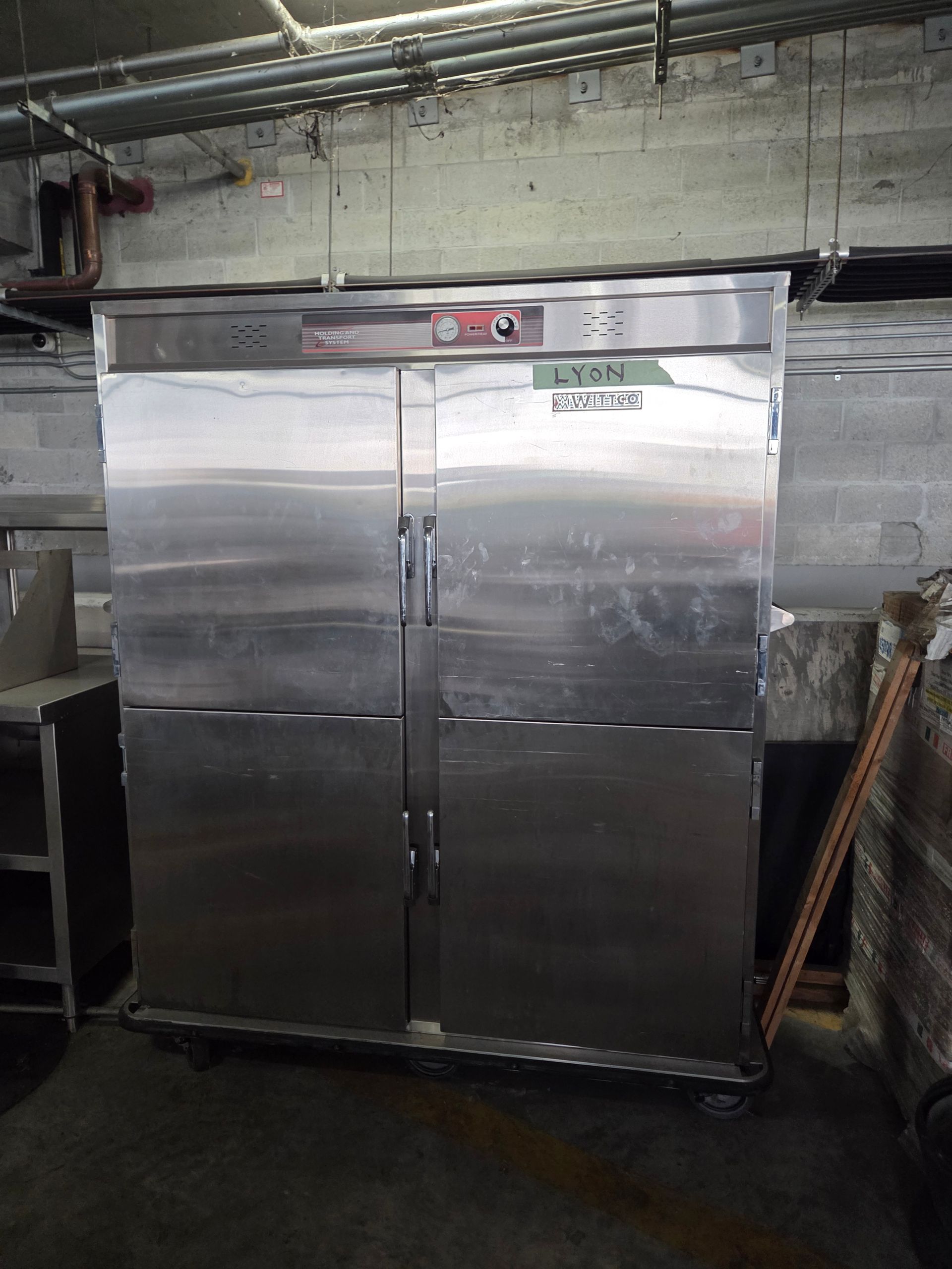 Stainless steel commercial refrigerator with four doors in a storage room.