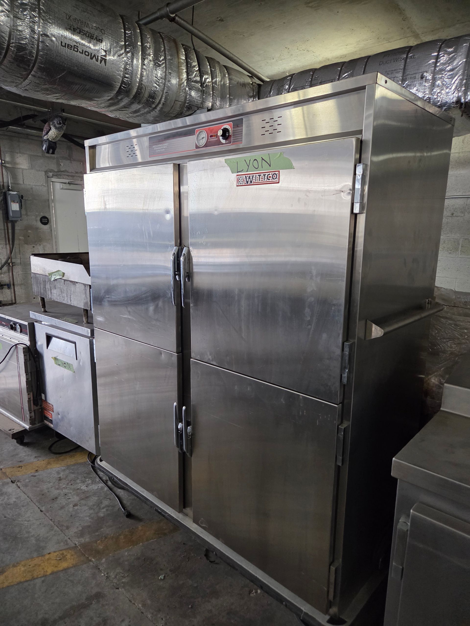 Stainless steel commercial food warmer with double doors in a kitchen.