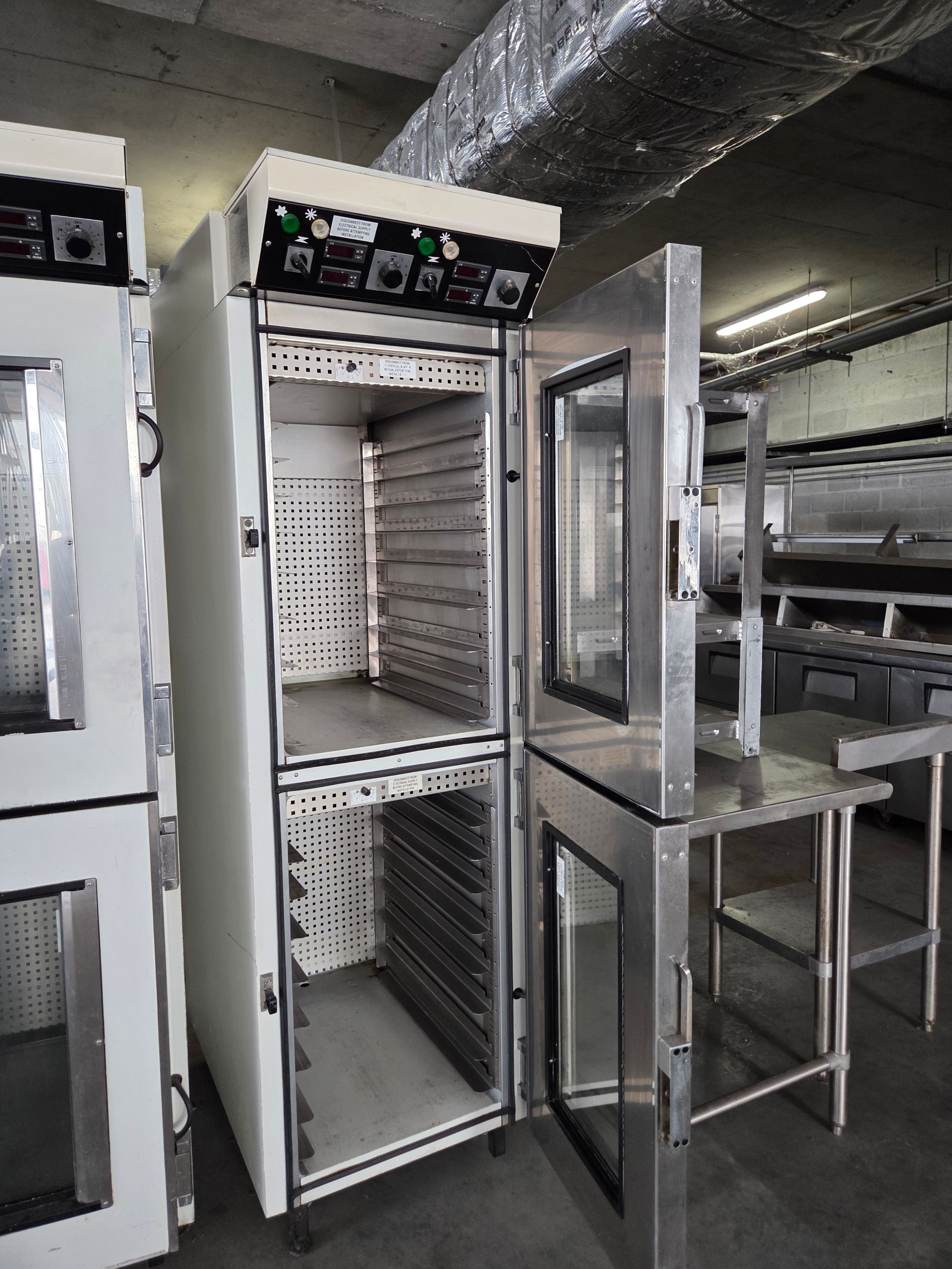 Commercial oven with open doors, stainless steel and white, in a kitchen.