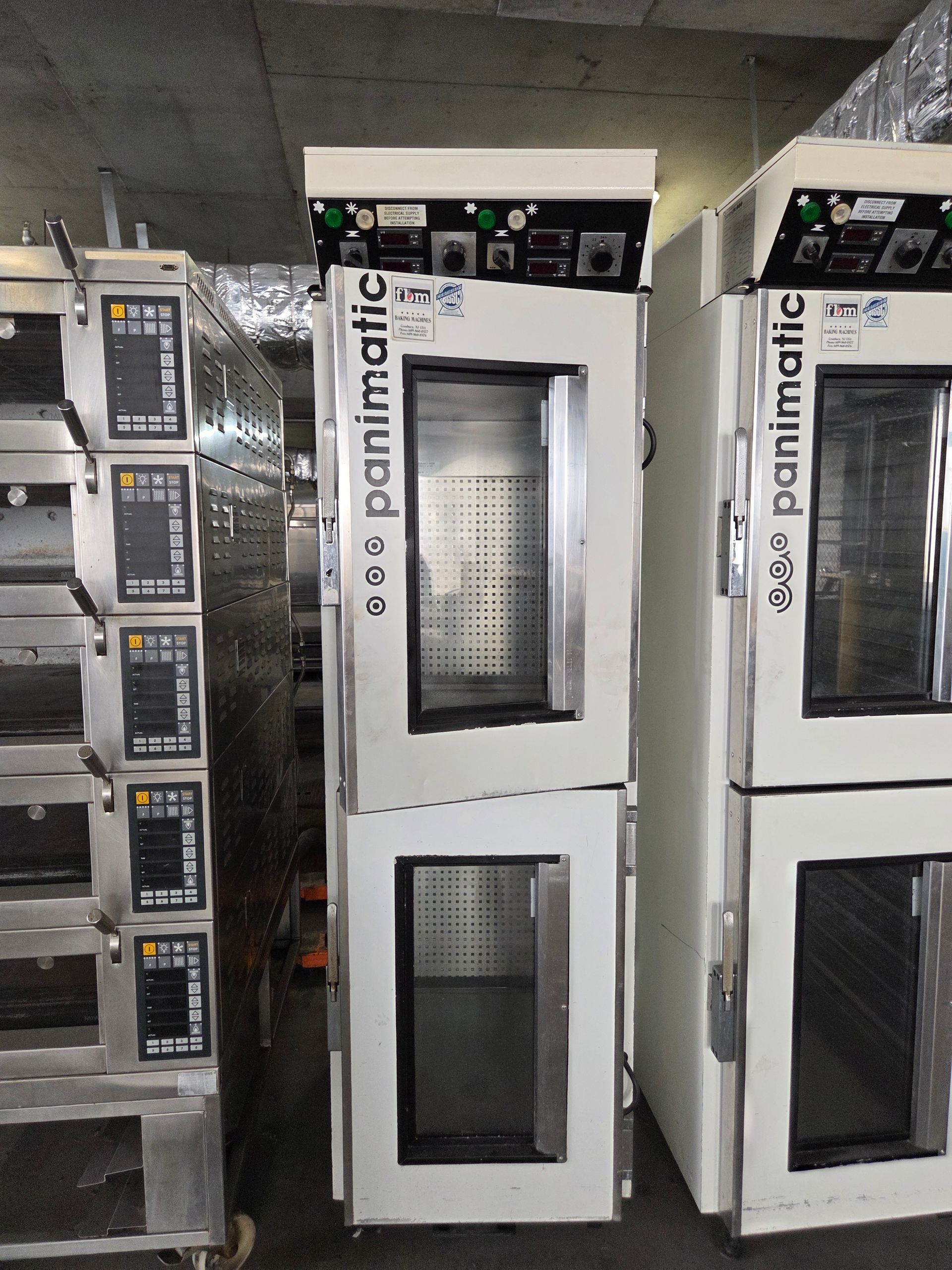 Three tall, white commercial ovens labeled 