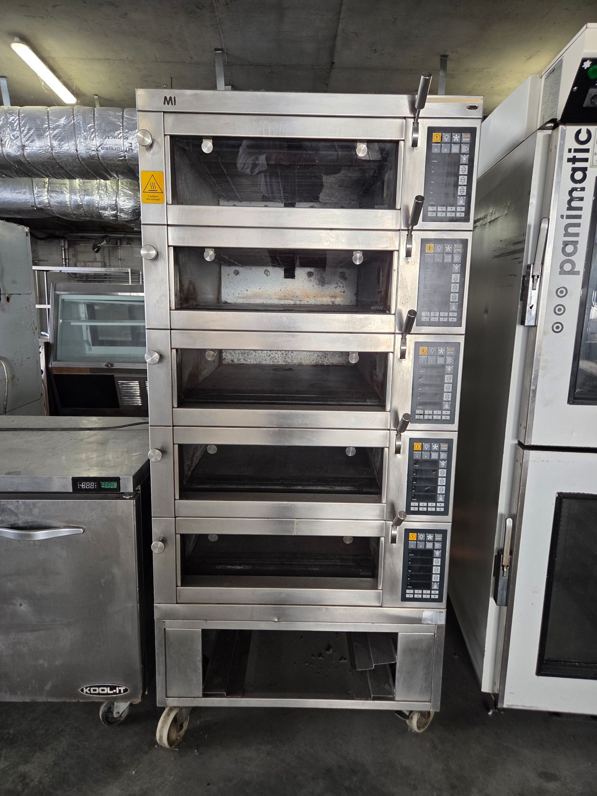 A multi-deck stainless steel commercial oven on wheels, with controls on the side.