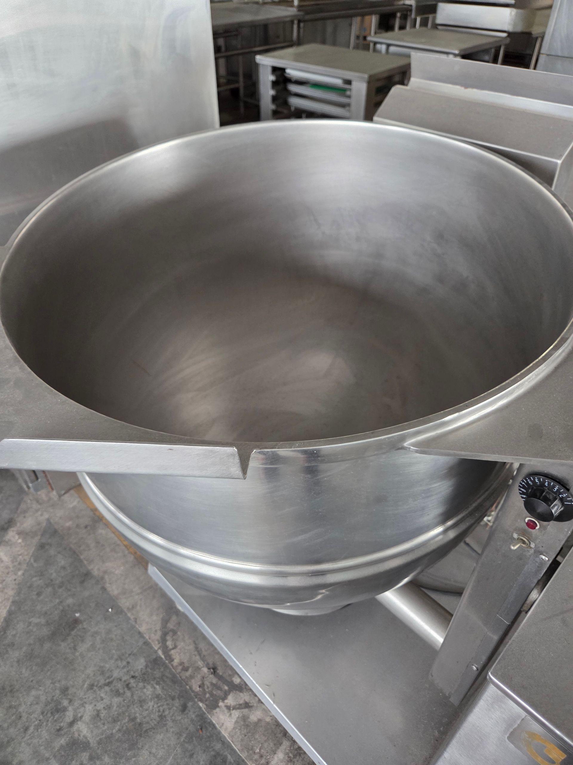 Large stainless steel commercial cooking kettle in a kitchen setting.