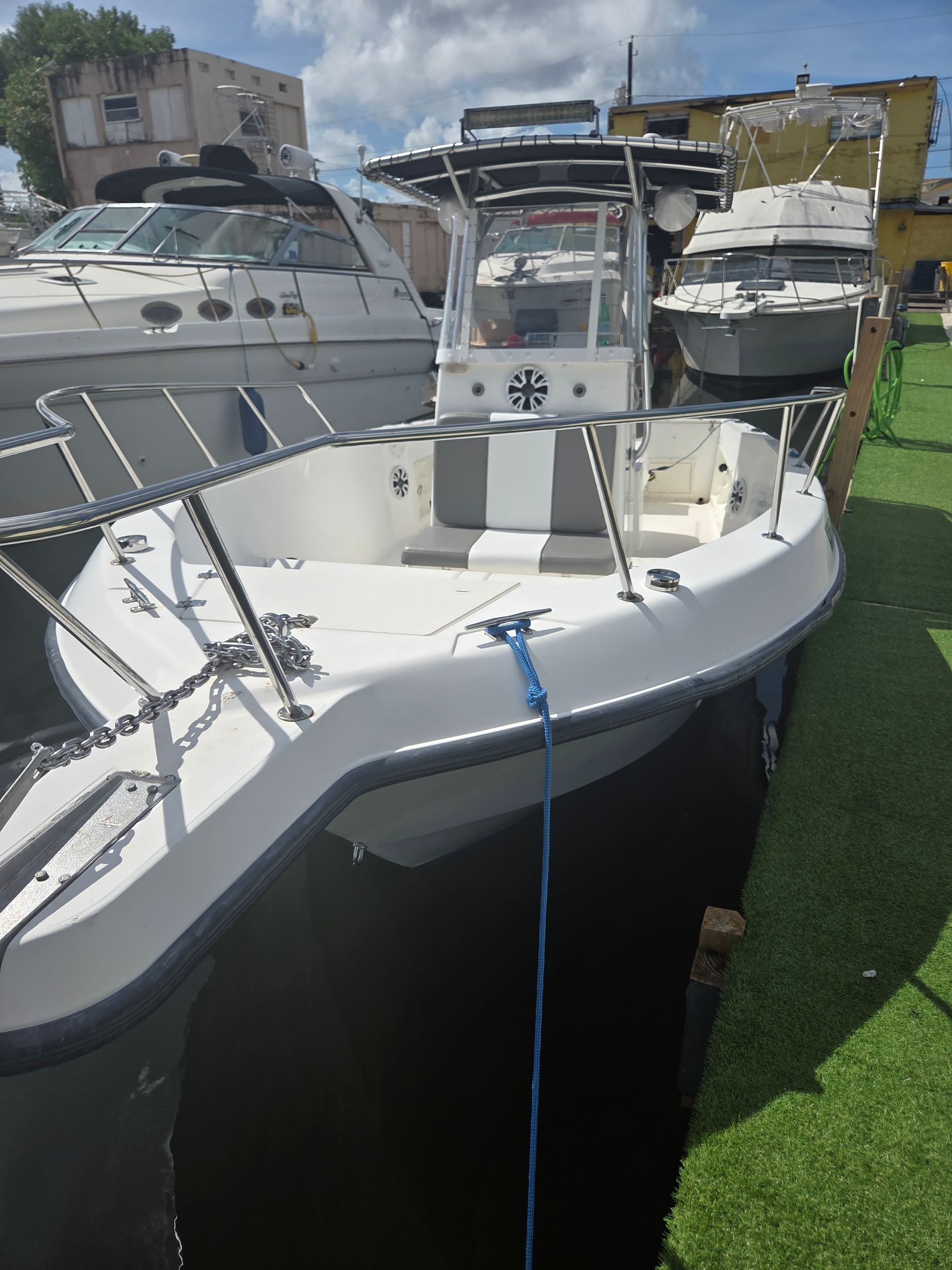 White motorboat docked next to other boats, a sunny day.