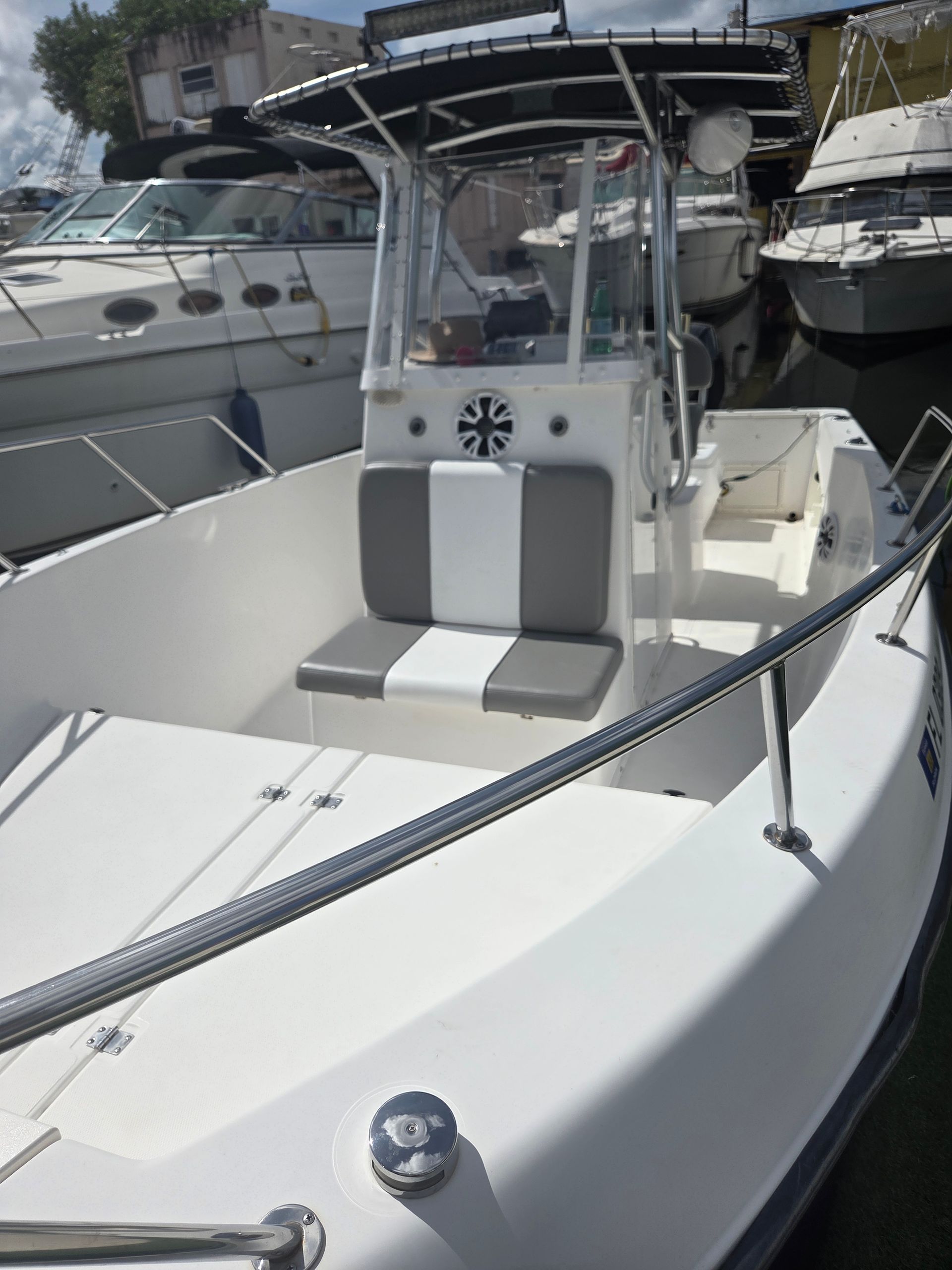 White center console boat with a black and gray interior, docked near other boats.