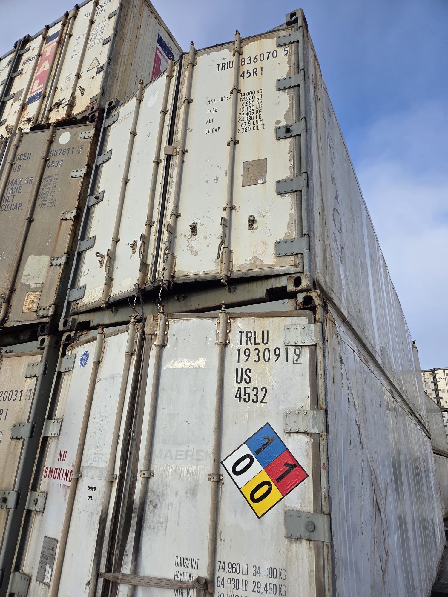 Stacked white shipping containers with a hazardous materials diamond.