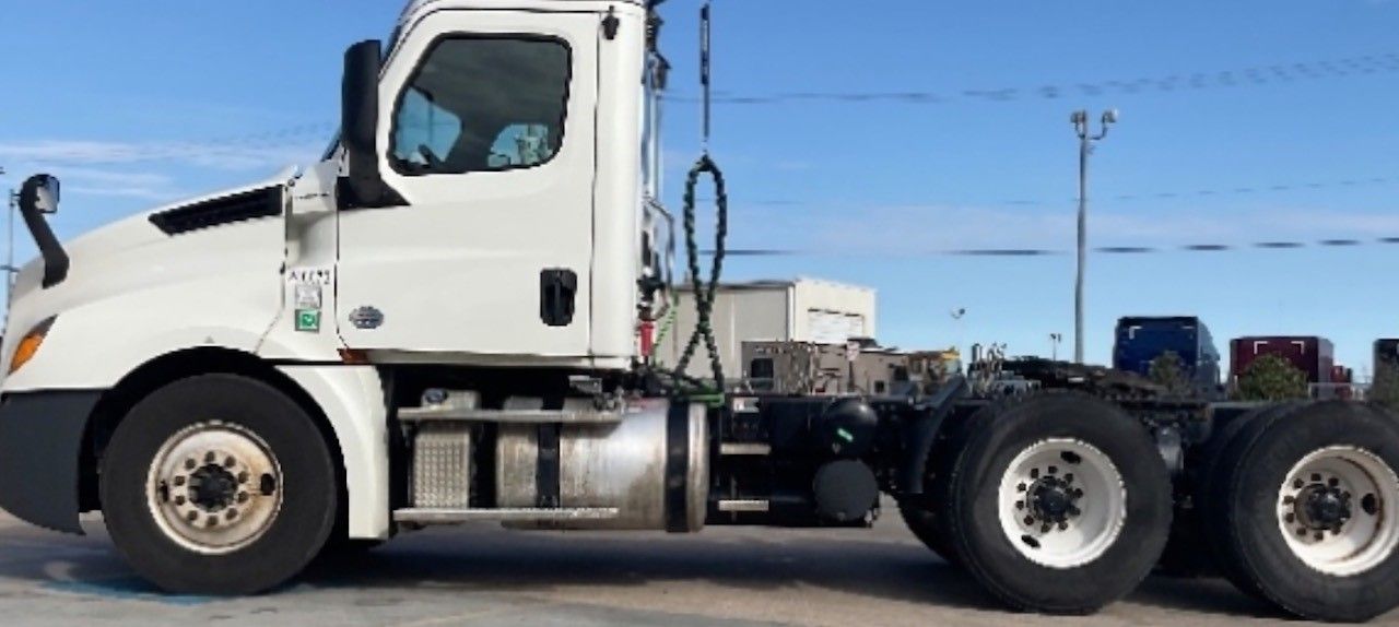 White semi-truck parked outside on a bright, clear day.