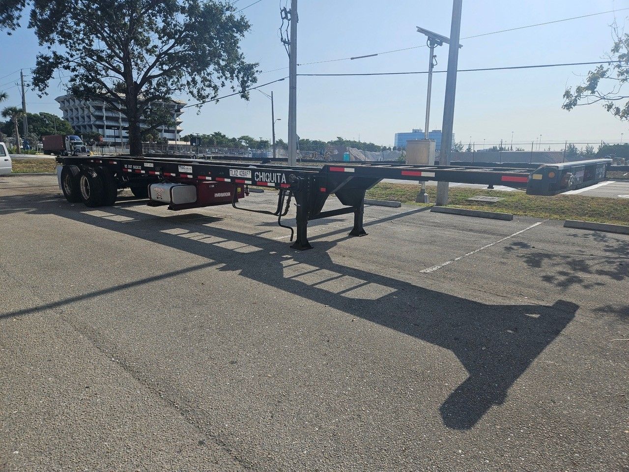 Empty black container chassis trailer parked on pavement.