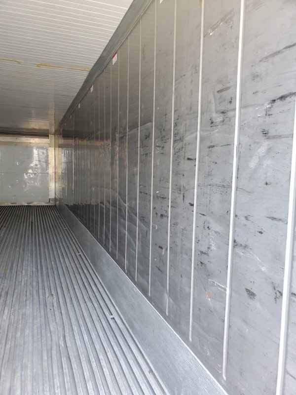 Interior view of a refrigerated truck, showing metal walls and ridged floor.