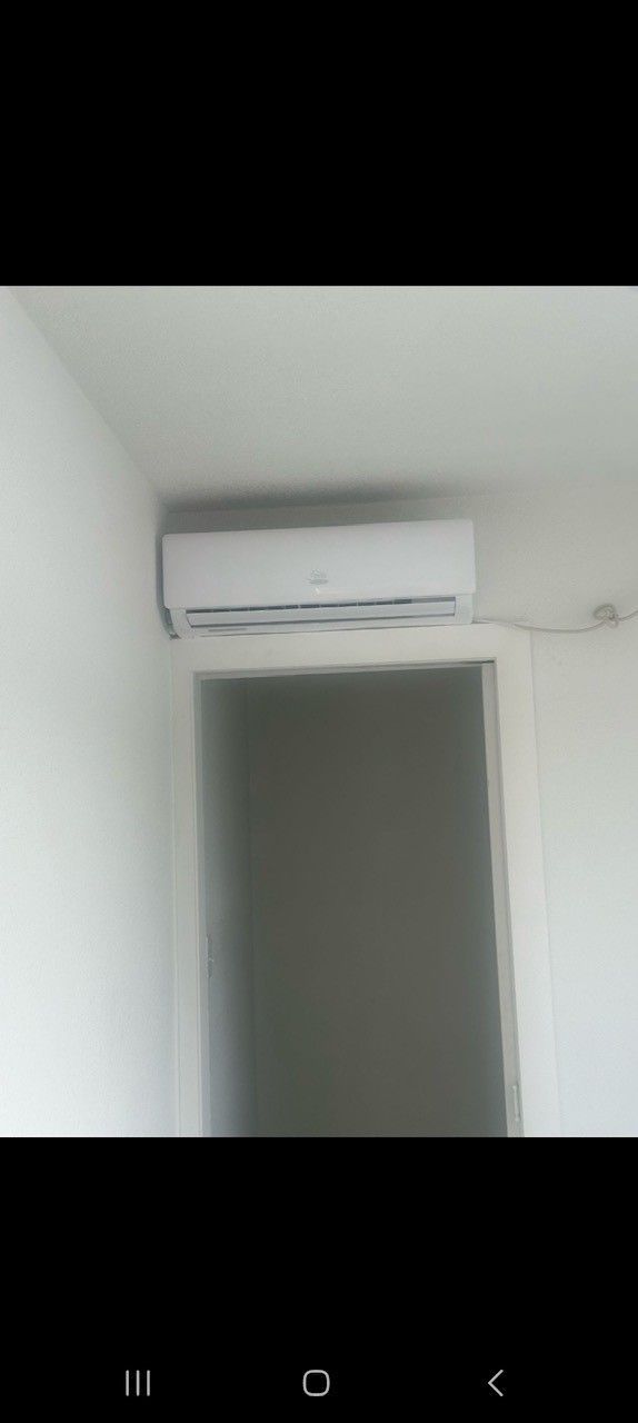 An air conditioning unit mounted on a white wall above a doorway.