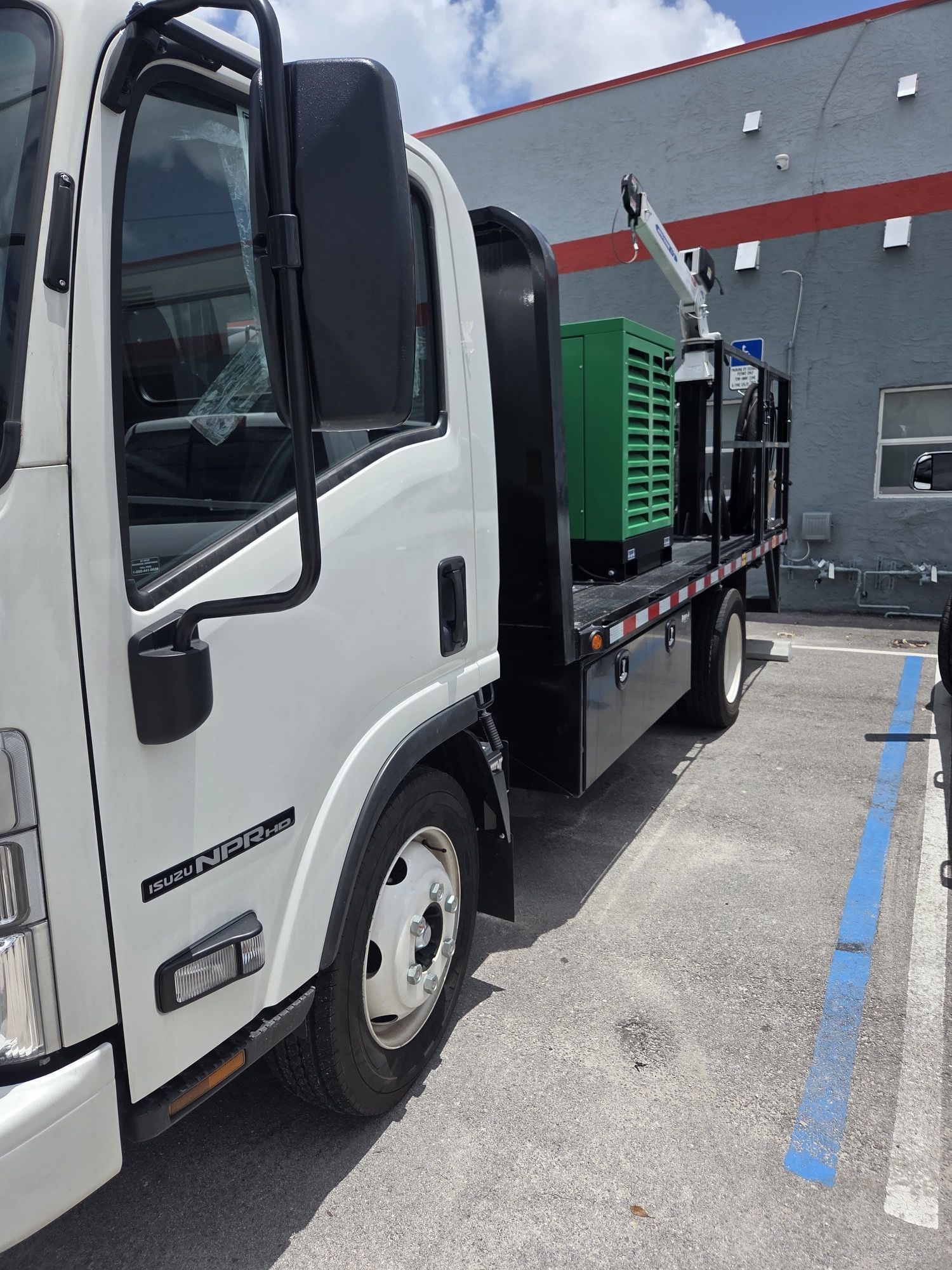 White truck parked in a lot. A large green item is on the flatbed.