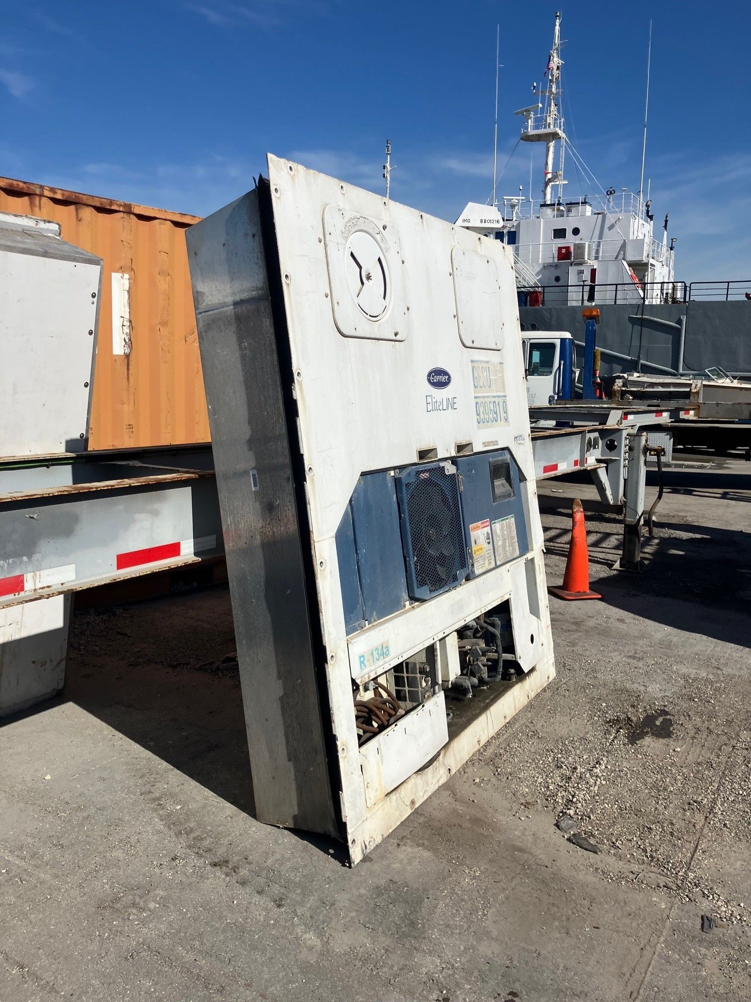 White Carrier refrigeration unit on a concrete surface near a trailer and a boat.