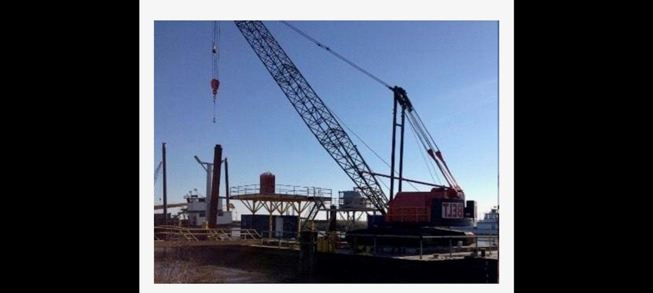 A crane on a construction site with blue sky overhead.