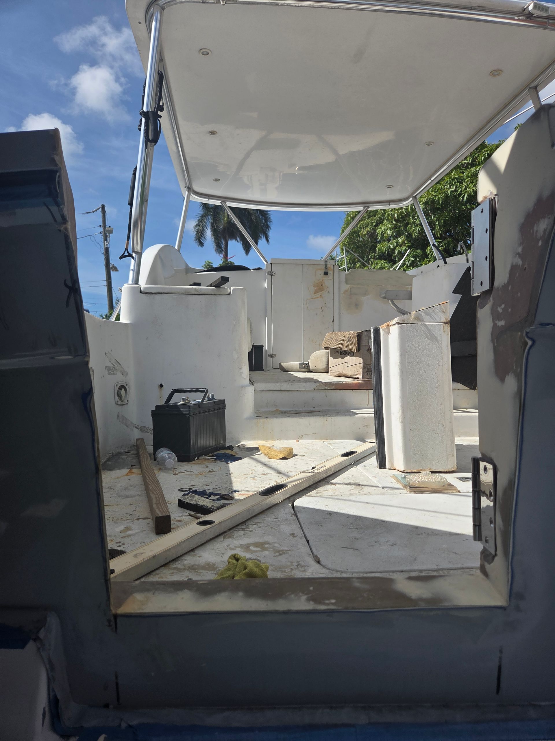 Interior of a boat under renovation, showing white structures, tools, and a gray floor.